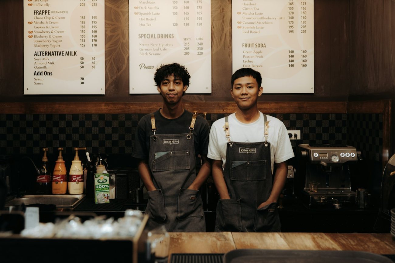 Two young baristas behind a counter