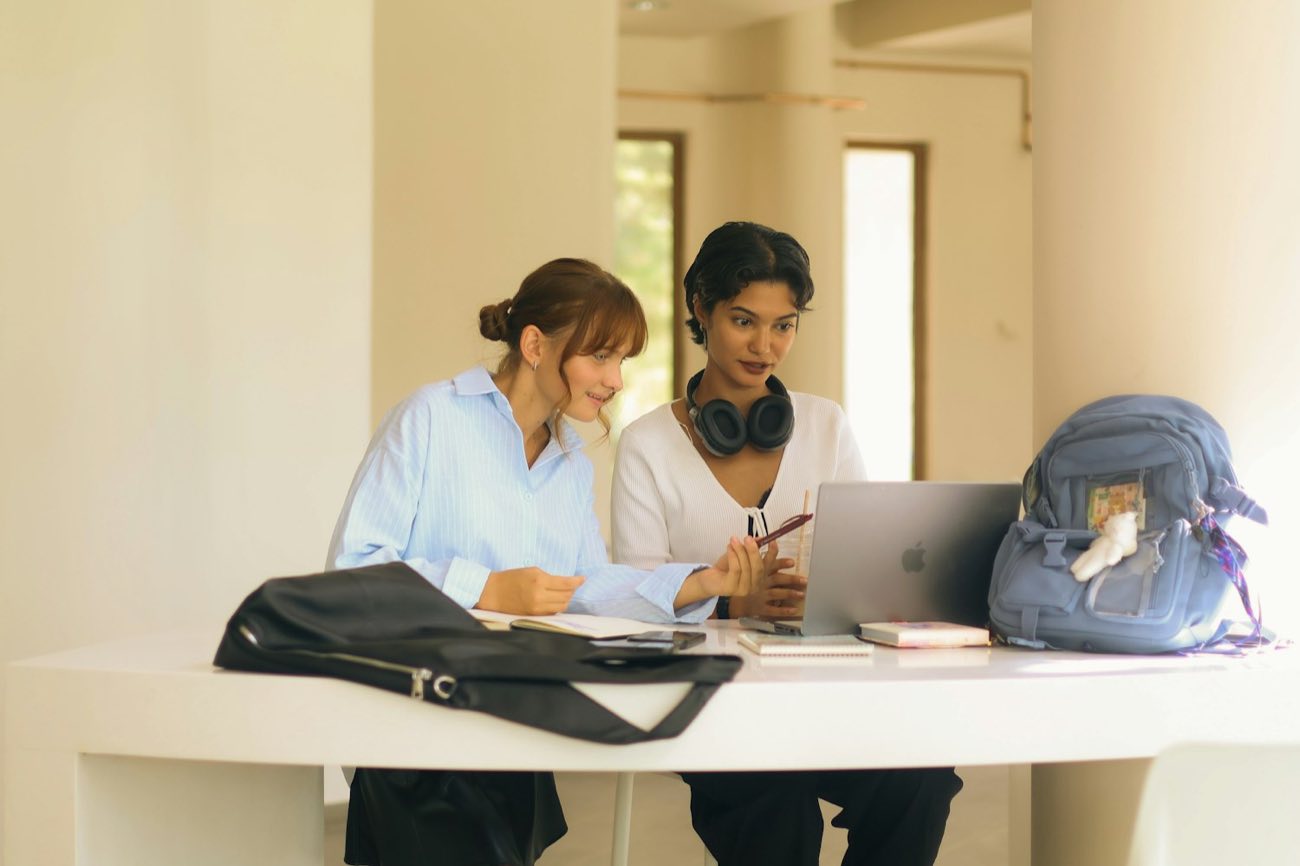 Students at a table with laptops and bags